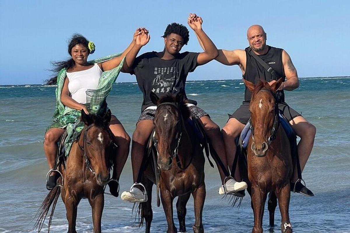 Un grupo de tres personas montando a caballo en la playa.