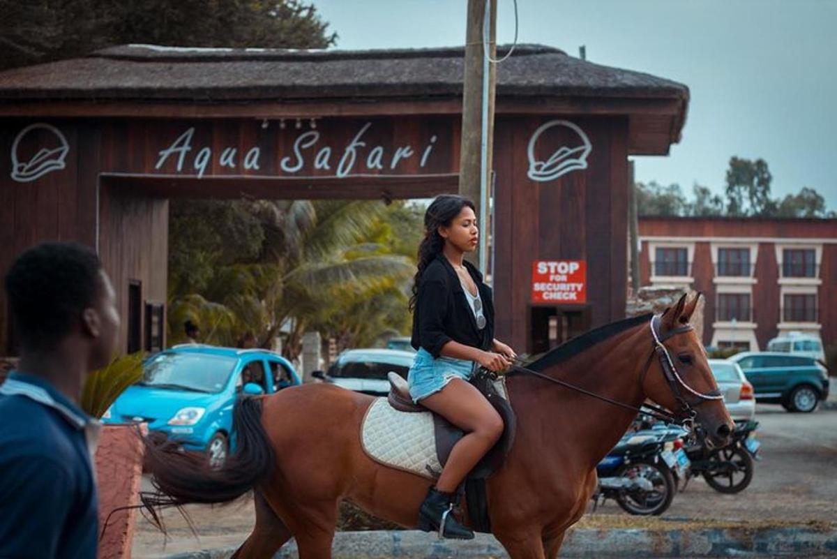 Una mujer montando a caballo frente a una tienda
