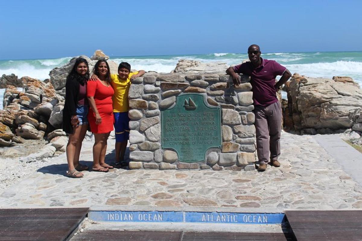 a group of people standing next to a sign on the beach