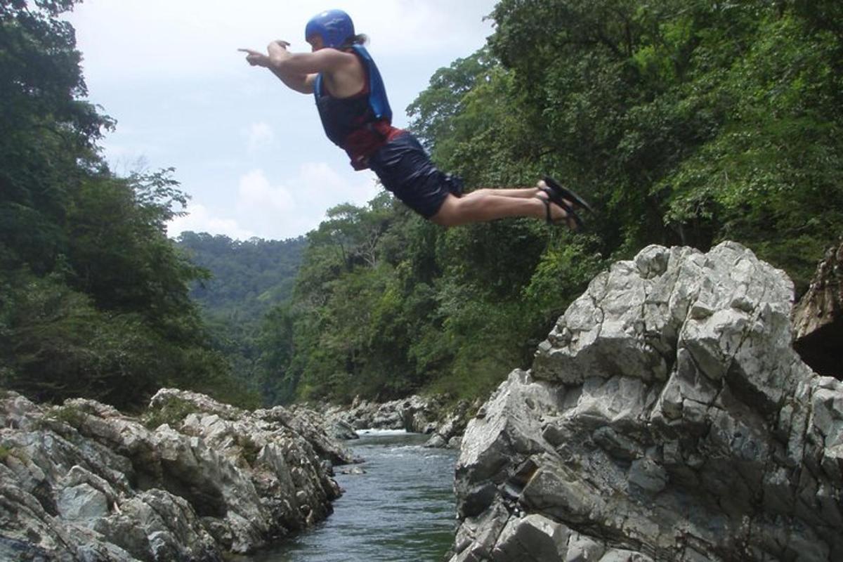un hombre saltando de una roca a un río