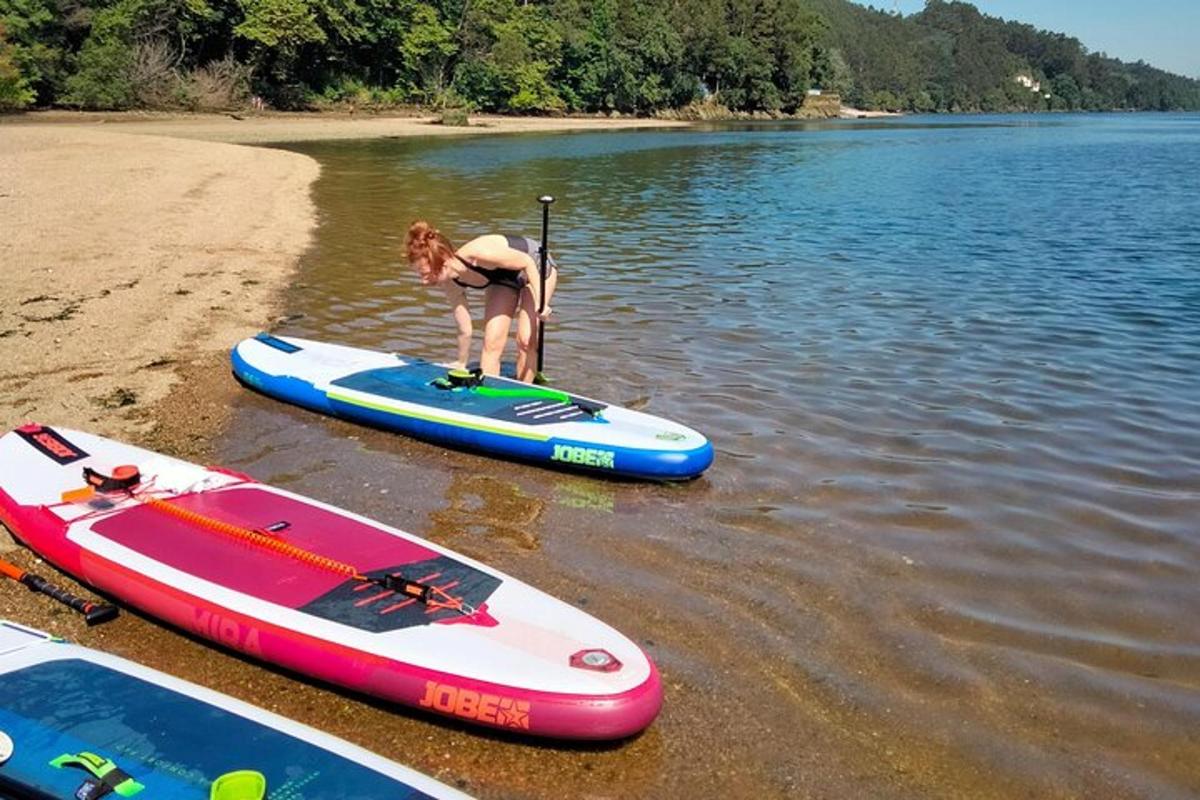 una dona dreta sobre una taula de paddle surf a l'aigua