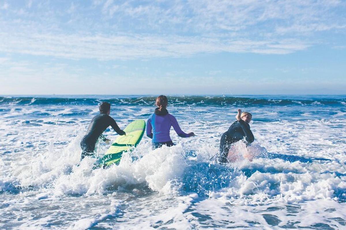 Tre personer i havet med surfbrädor i vattnet