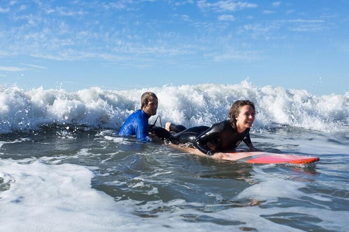 två personer som ligger på en surfbräda i havet