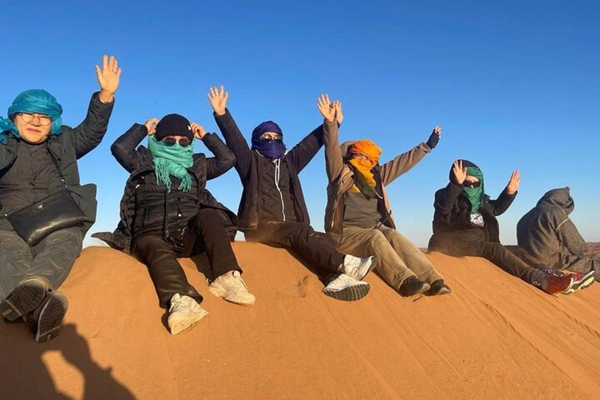 a group of people sitting on top of a sand mound