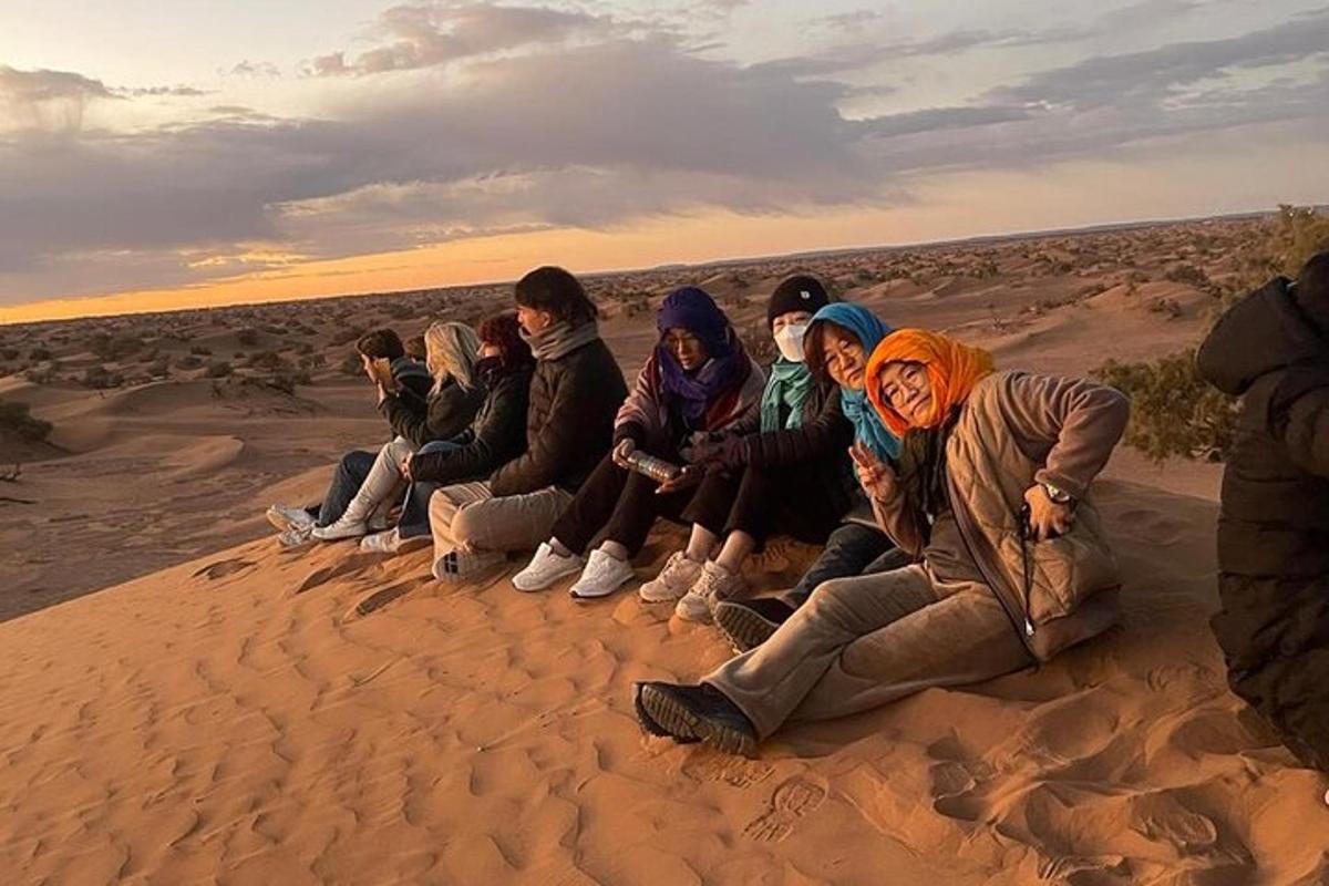 a group of people sitting on the sand in the desert
