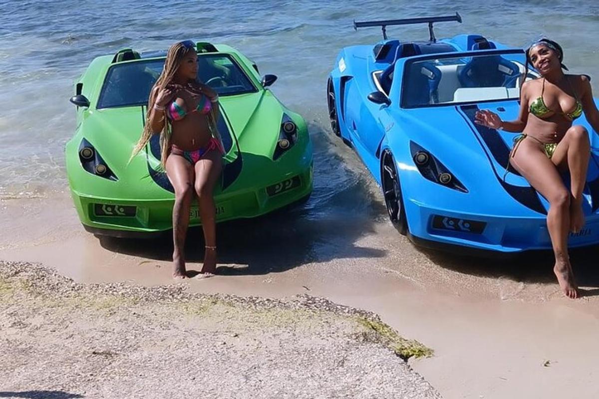 Dvě ženy v plavkách stojící vedle dvou aut na pláži