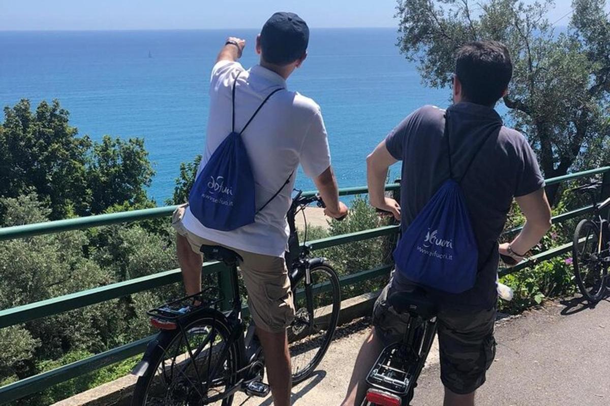 a group of three men on bikes looking at the ocean