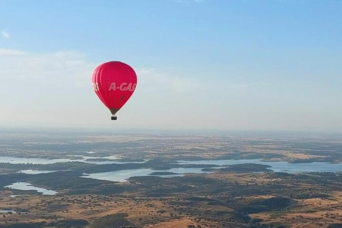 raudonas oro balionas, skrendantis virš upės