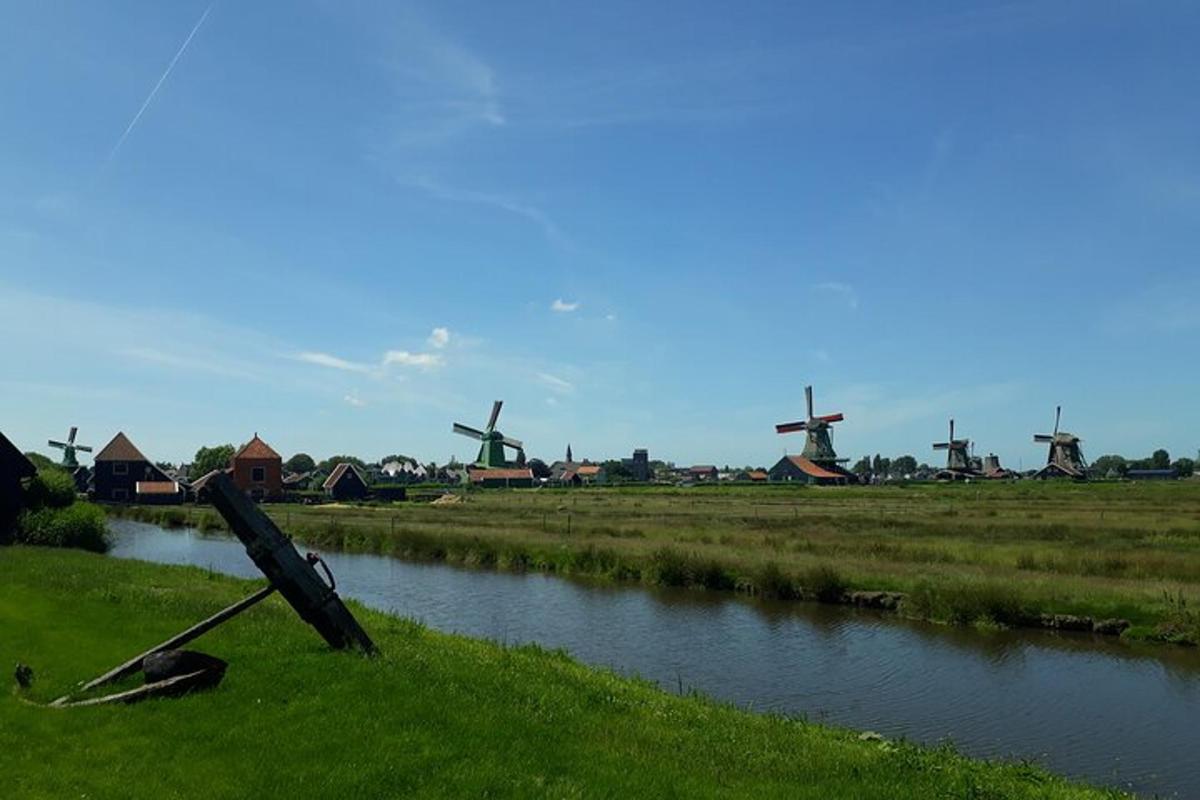 a boat laying on the grass next to a river with windmills