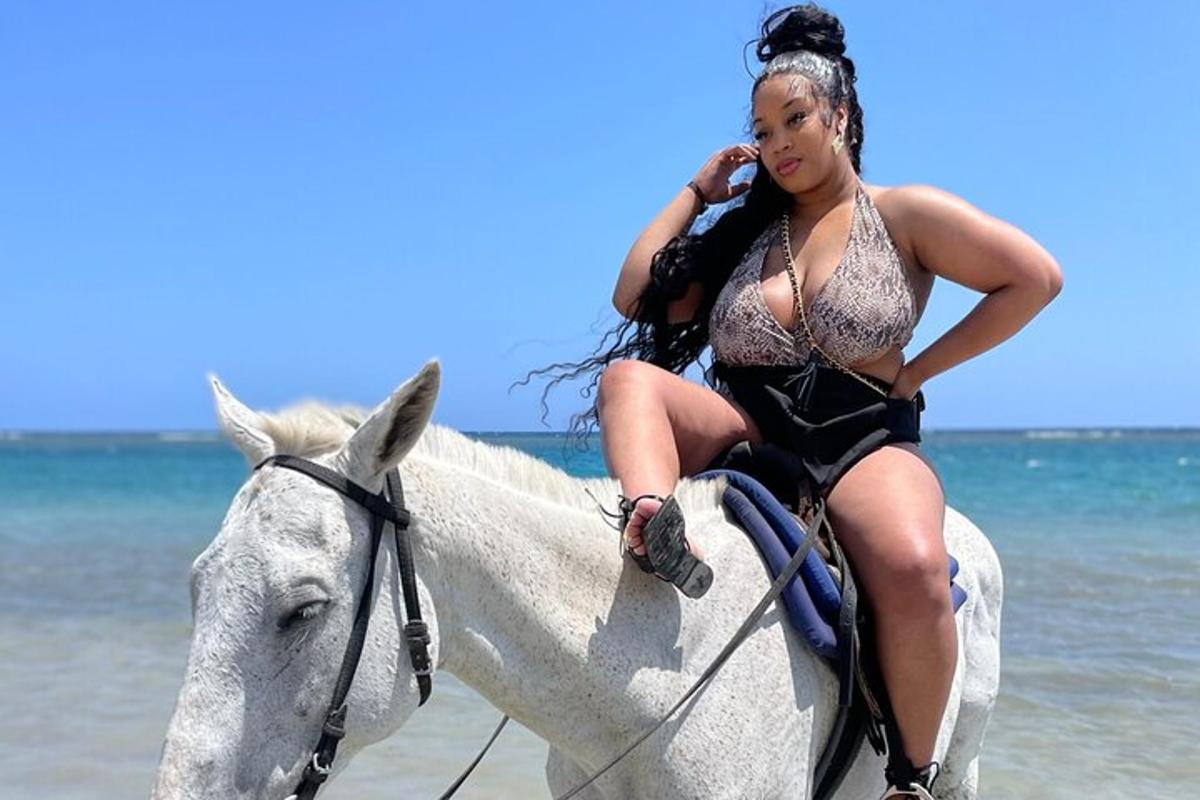 una donna a cavallo sulla spiaggia mentre parla al cellulare