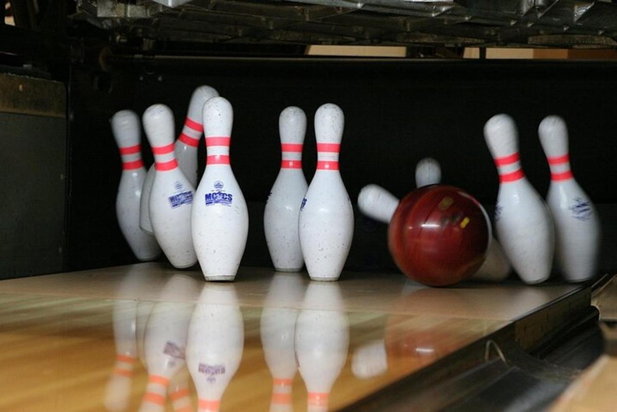 Skupina kuželek a jablko na bowlingové dráze
