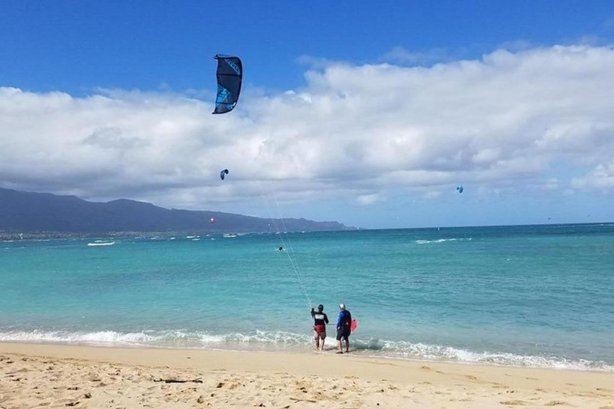 Dos personas de pie en una playa volando una cometa