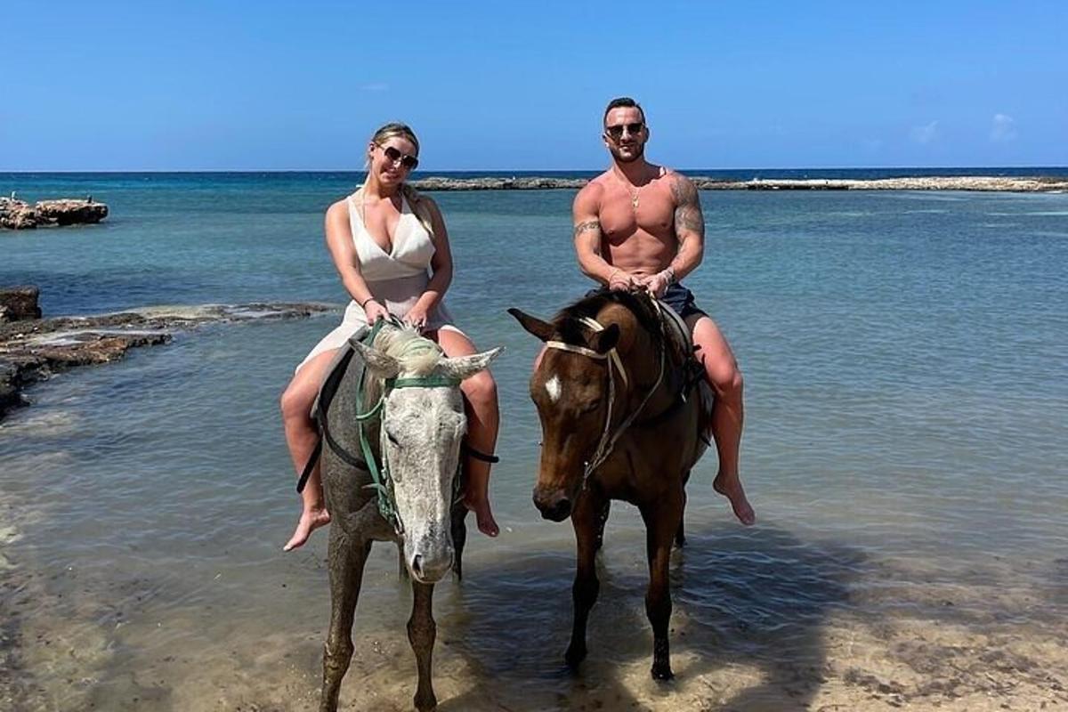 um homem e uma mulher cavalgando na praia
