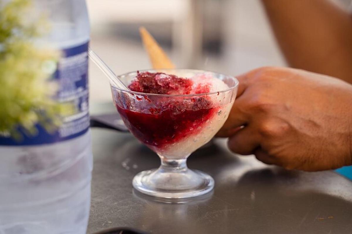 uma pessoa segurando uma bebida em um copo ao lado de uma garrafa