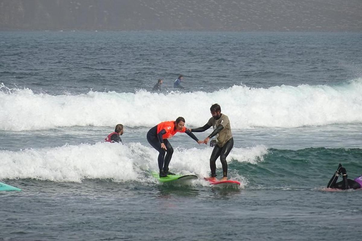 to personer rider på en bølge på surfbrætter i havet