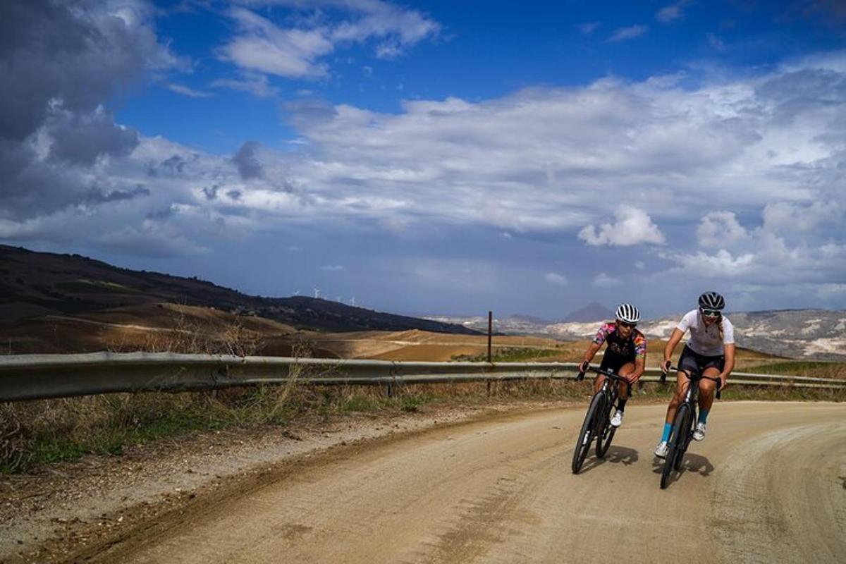 duas pessoas andando de bicicleta em uma estrada de terra