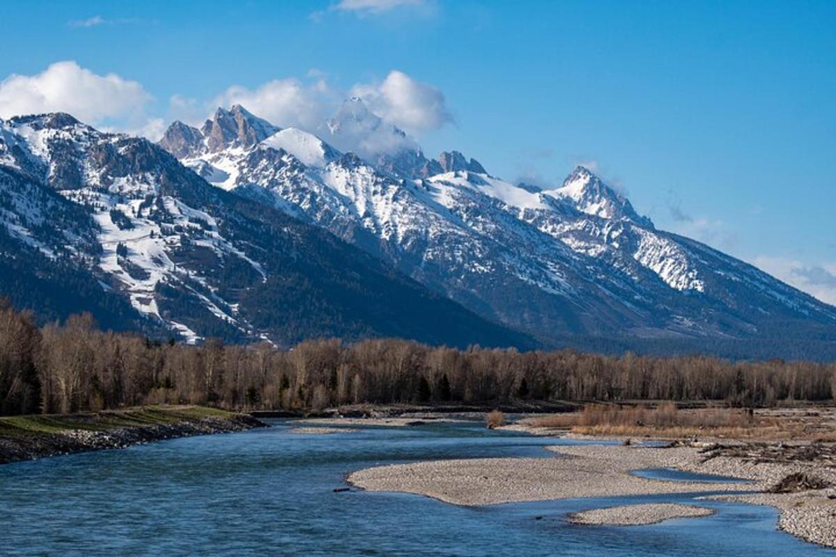 Un río con montañas cubiertas de nieve al fondo