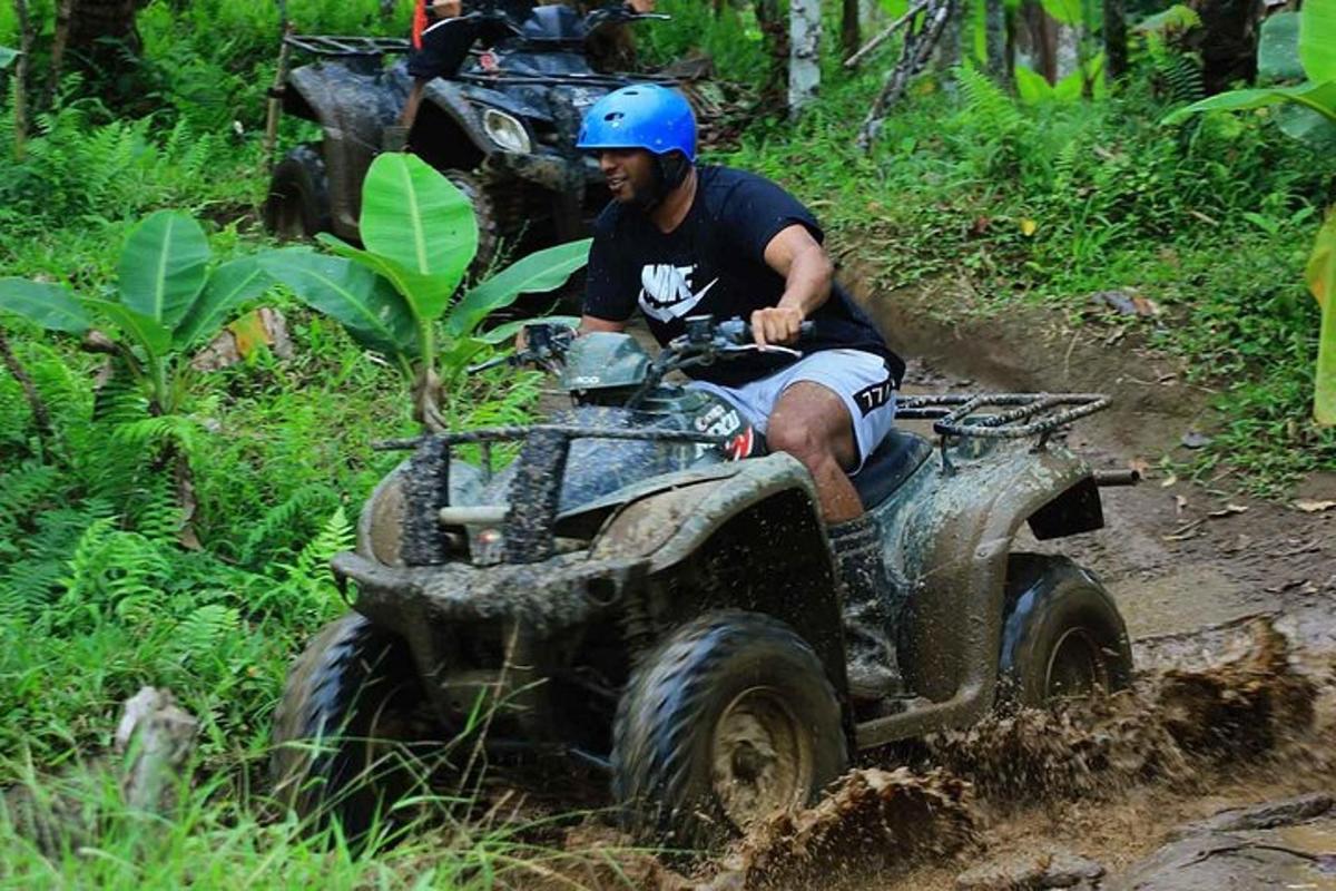 un uomo che guida un quad nel fango