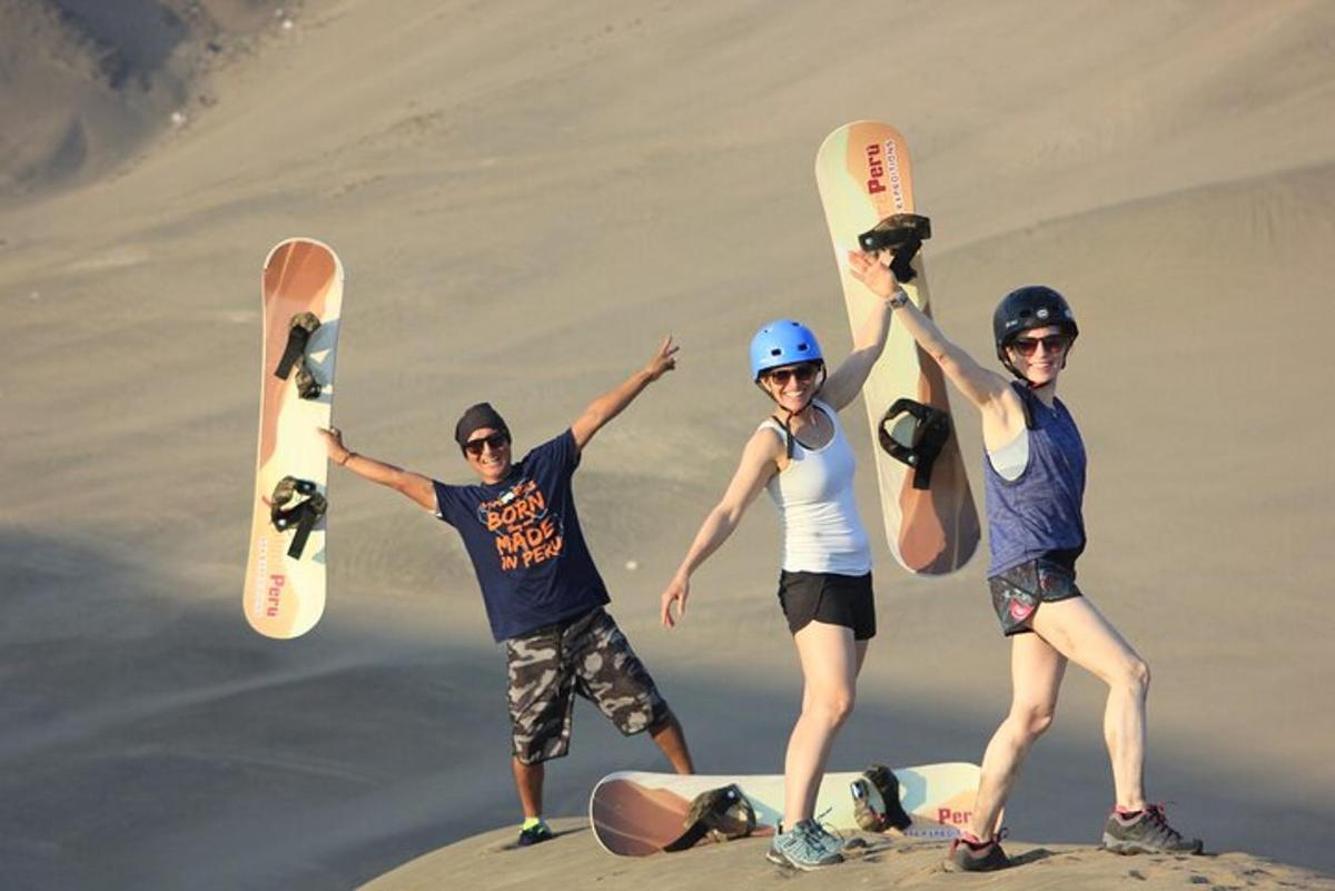 tatlong tao ang nagpo-pose kasama ang kanilang mga snowboard sa buhangin