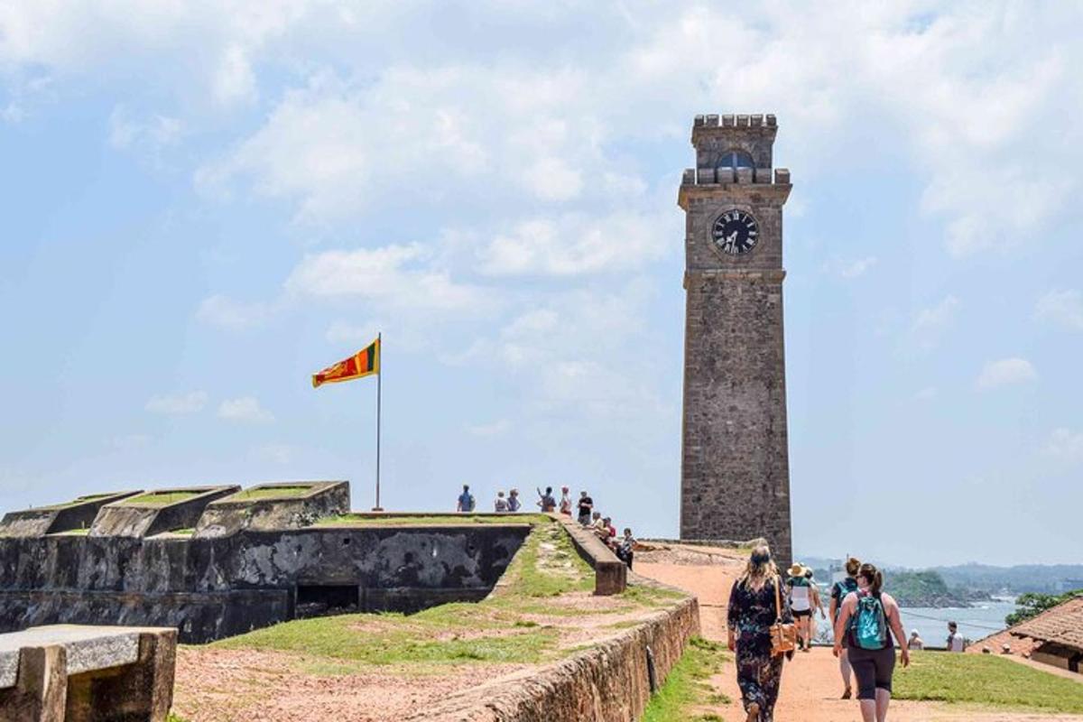 uma torre do relógio com uma bandeira e pessoas passando por ela