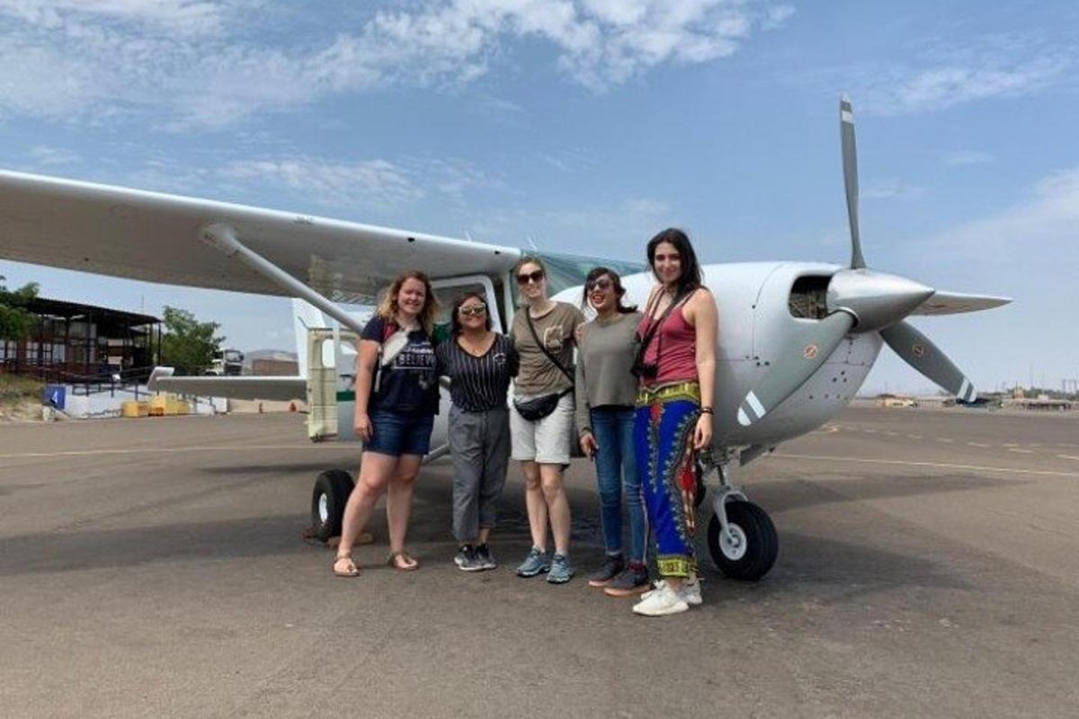 um grupo de pessoas em pé na frente de um avião