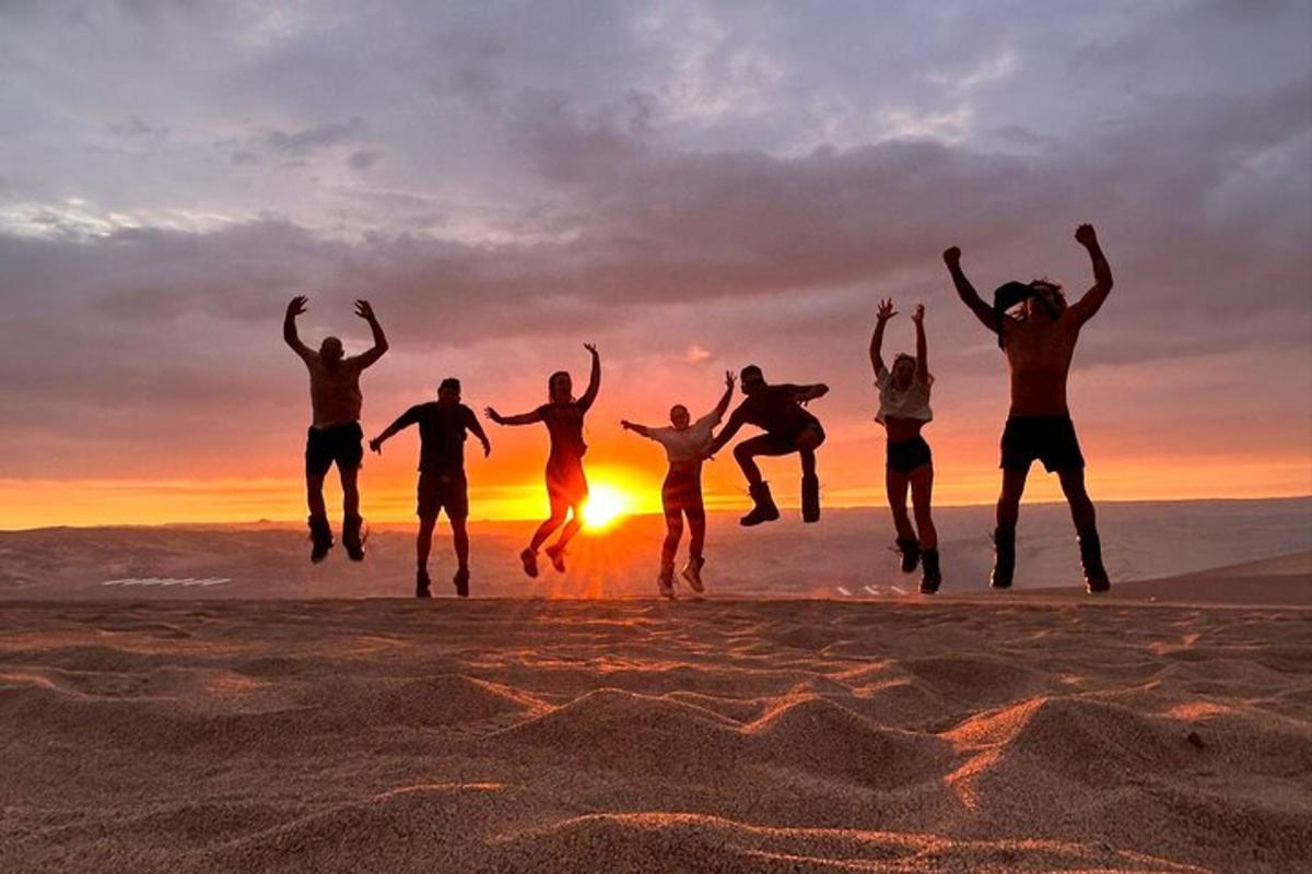 un grup de persones saltant a la platja a la posta de sol