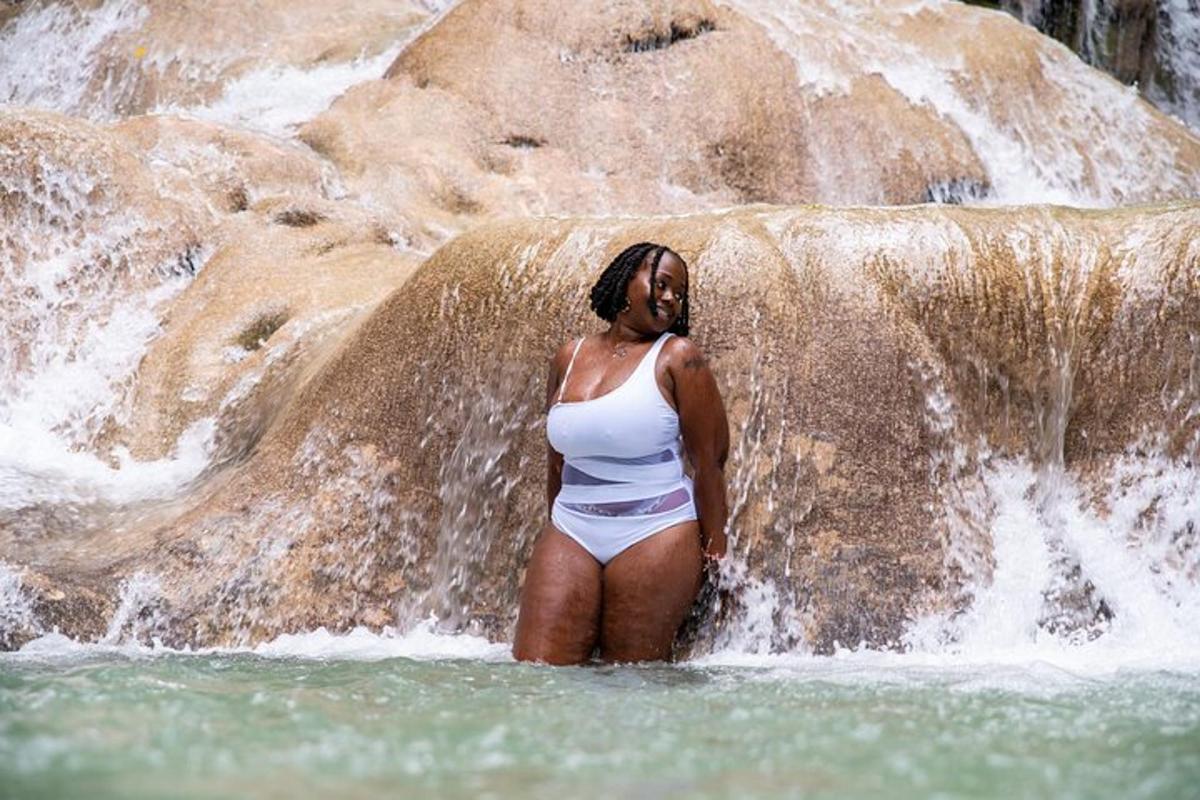 seorang wanita berdiri di dalam air di hadapan air terjun