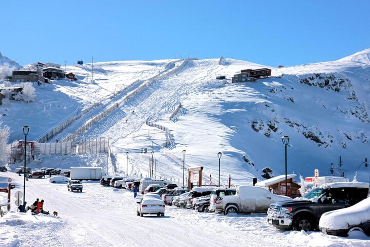 Un estacionamiento nevado con autos estacionados en una montaña cubierta de nieve