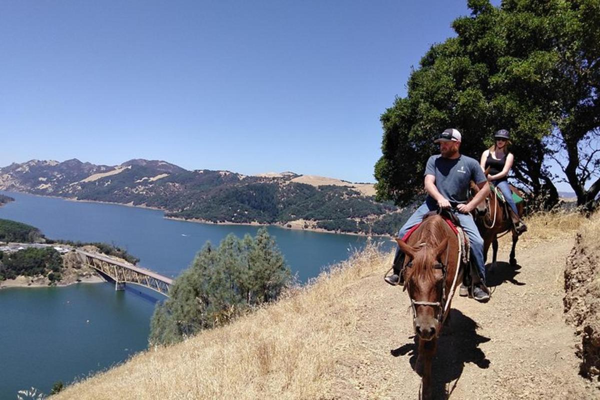 a man and a woman riding a horse on a hill