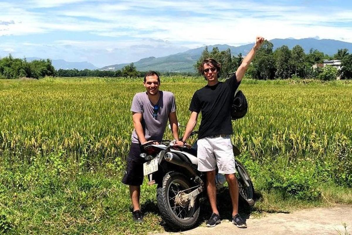 két férfi áll egy motorkerékpár mellett egy mezőn