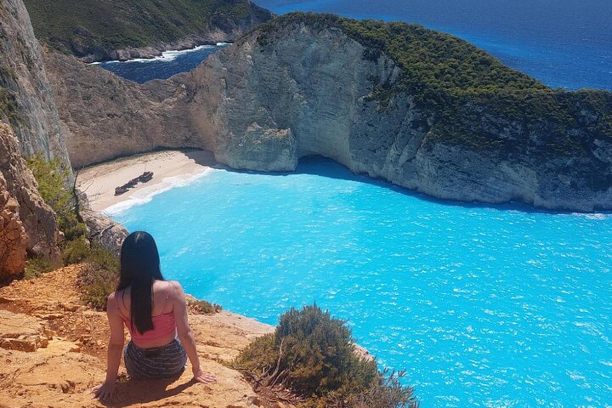 ženska sedi na pečini in gleda na plažo