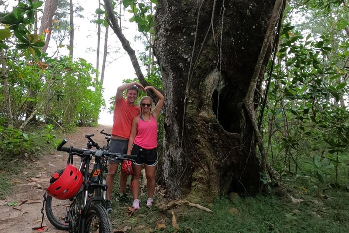 a man and woman standing next to a tree with a bike