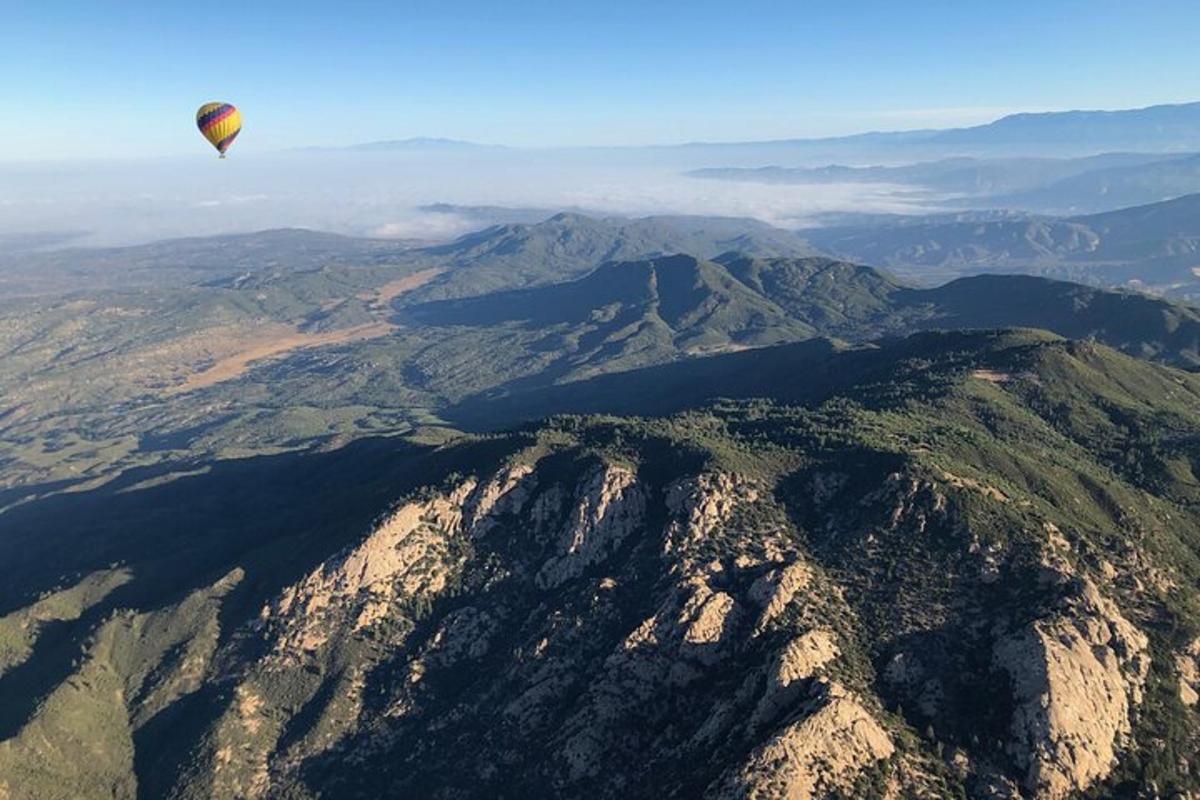 horkovzdušný balón letící nad pohořím