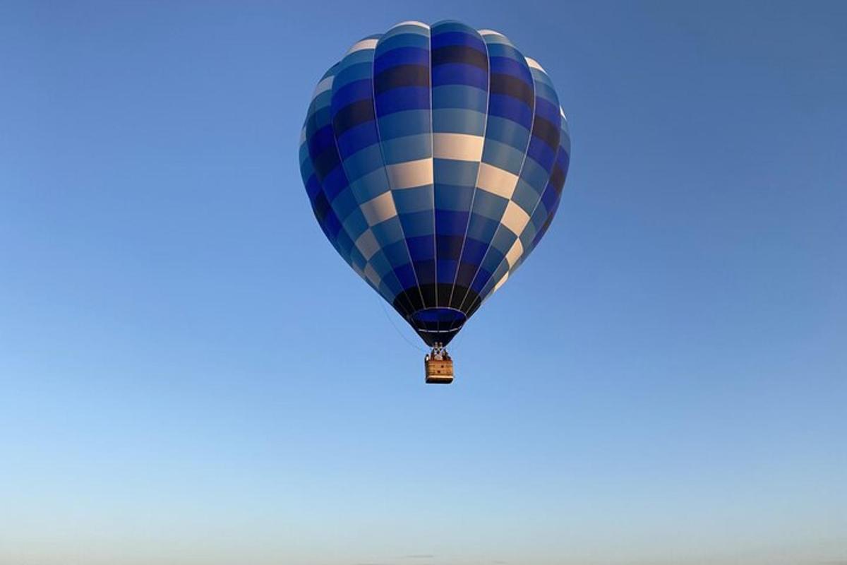 modrý horkovzdušný balón letící na obloze