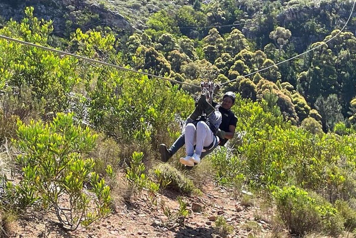 two people riding on a zip line on a hill