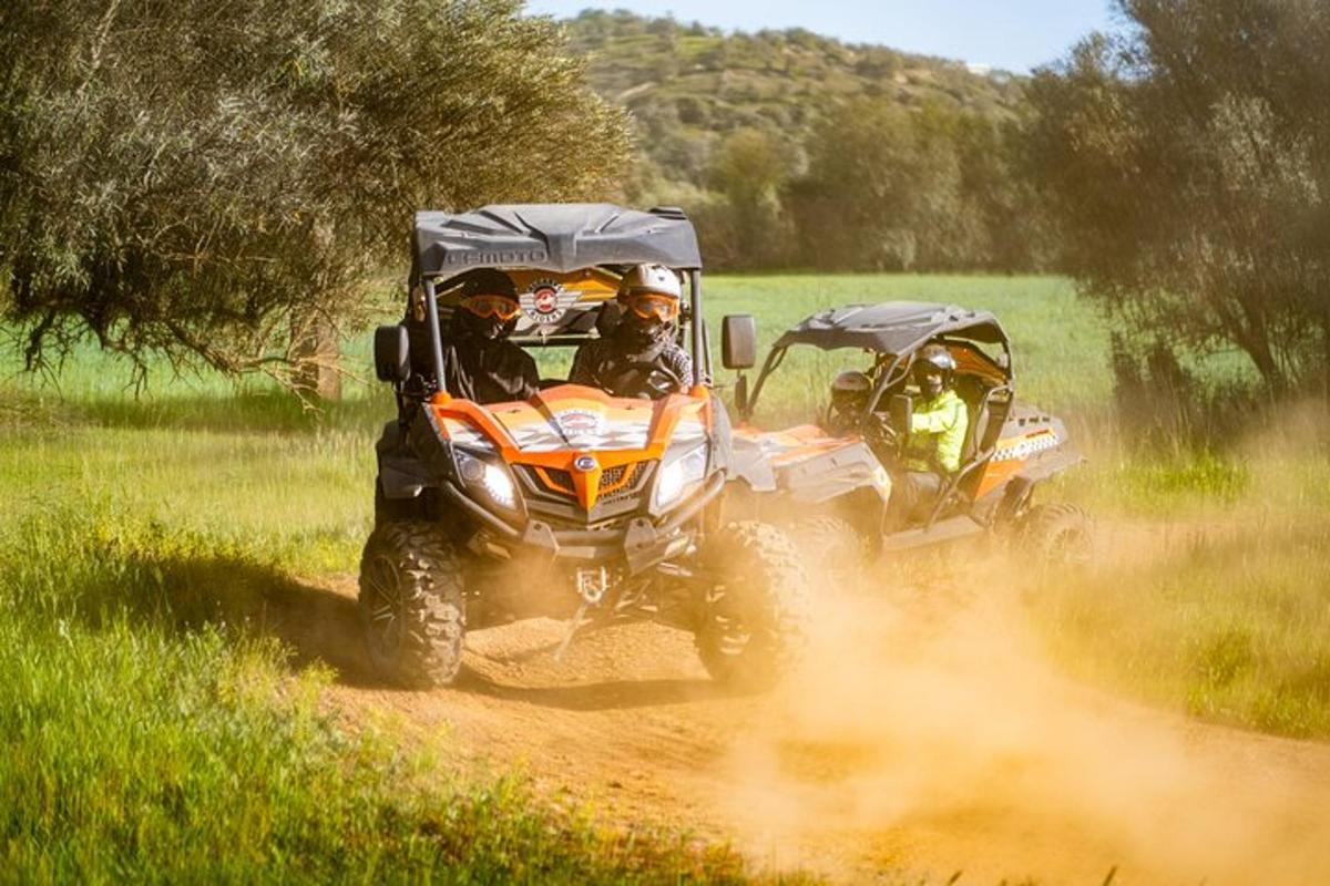 dues persones que condueixen quads per un camí de terra