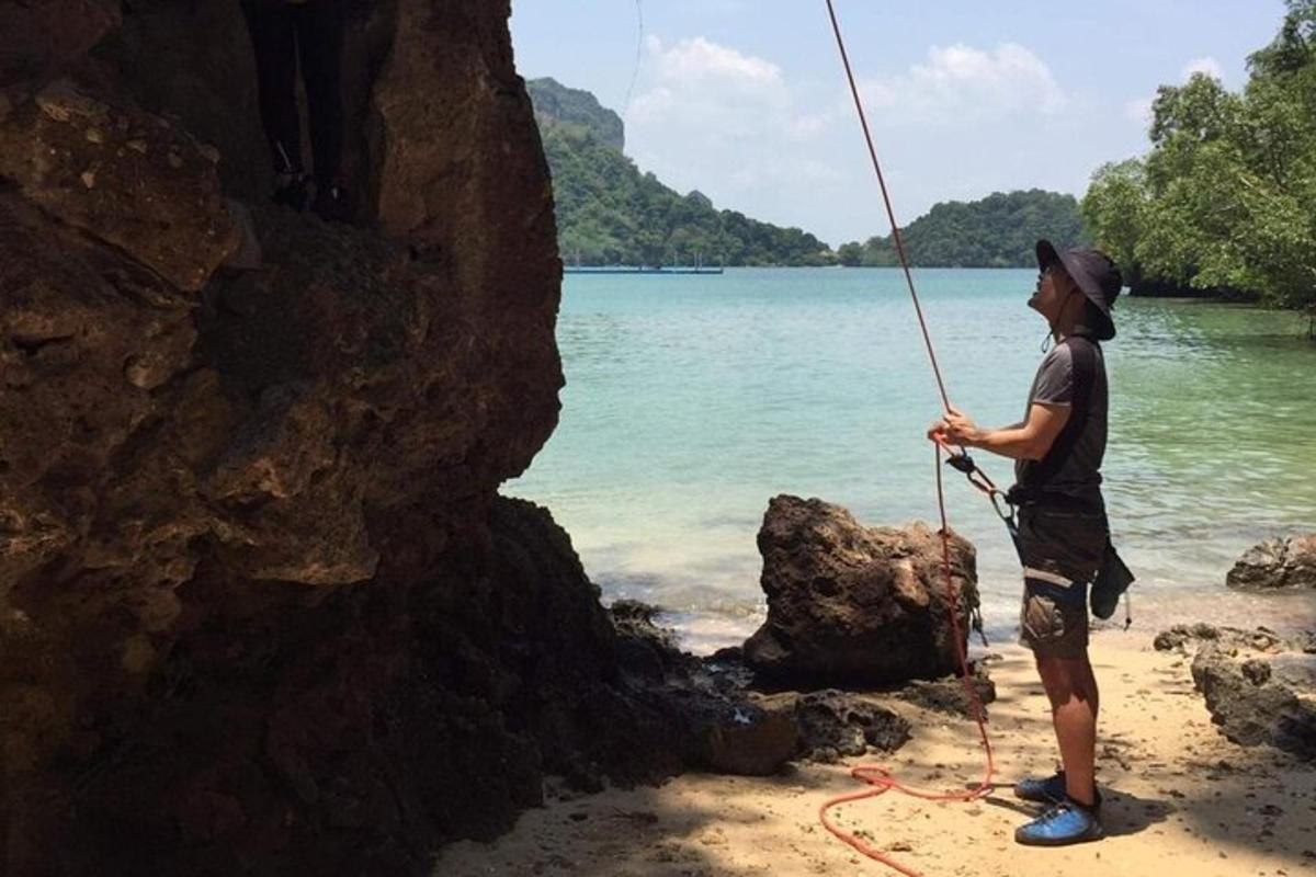 un uomo in piedi su una spiaggia che tiene una corda