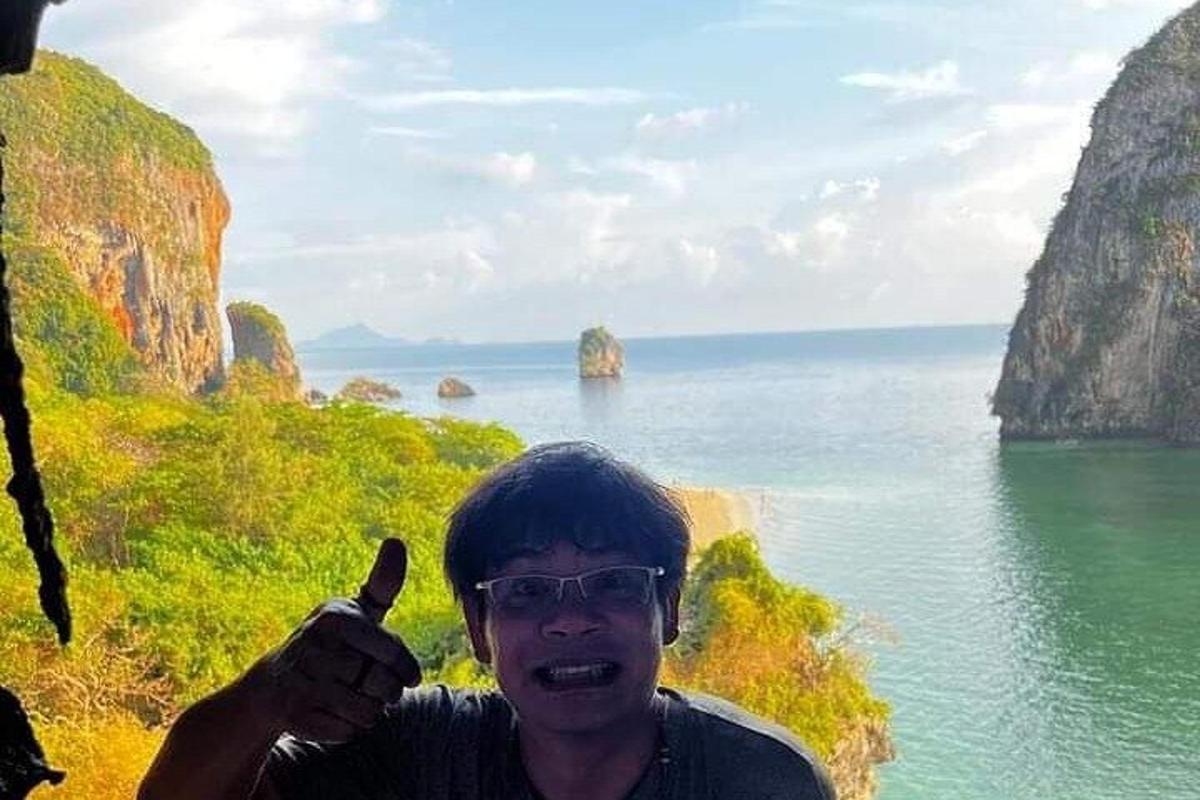 un uomo che fa il gesto del pollice in su davanti all'oceano