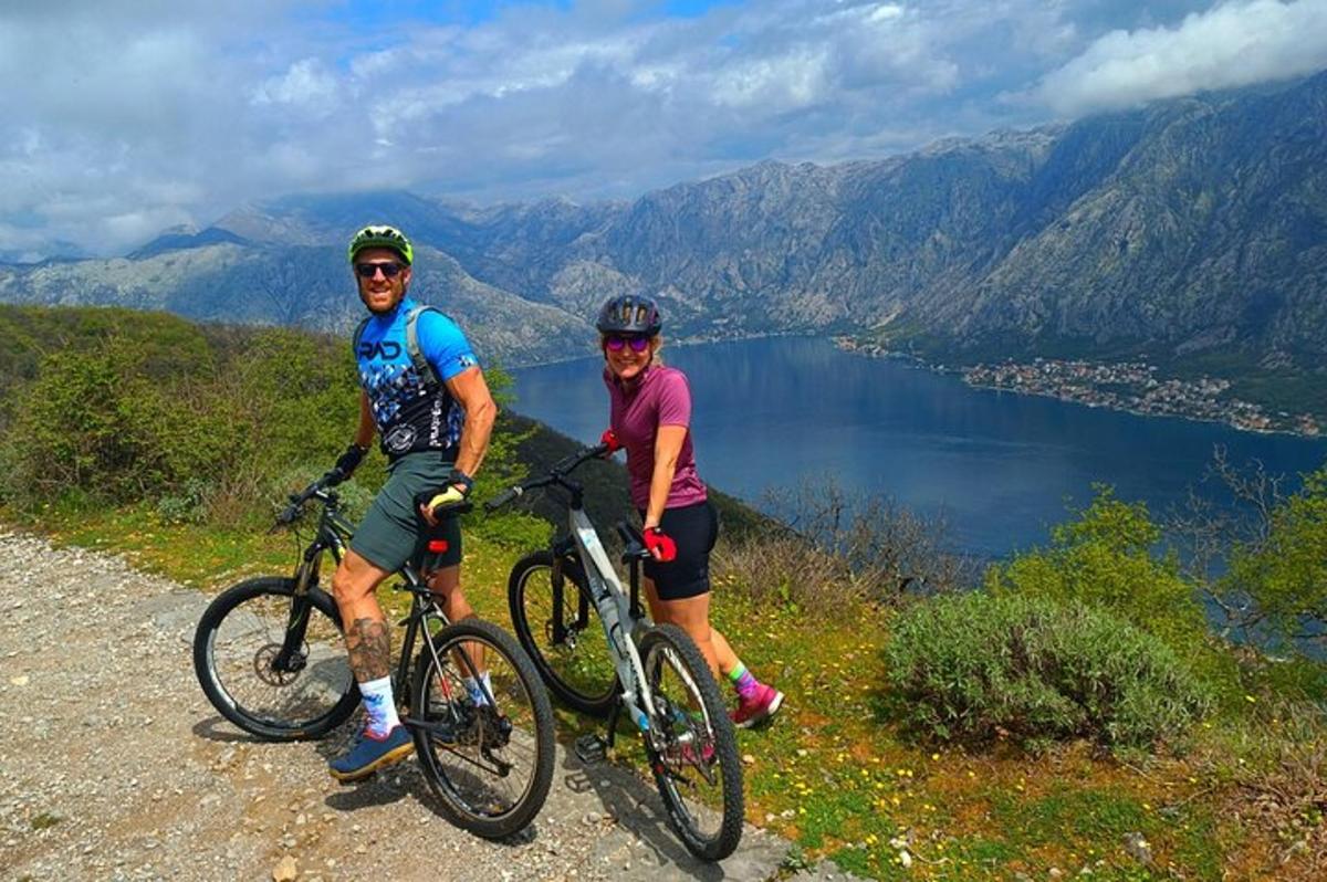 dva lidé na kolech na kopci s výhledem na jezero