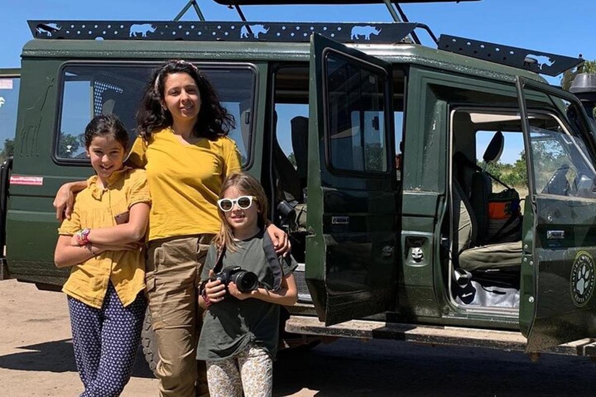 a woman and two girls standing in front of a vehicle