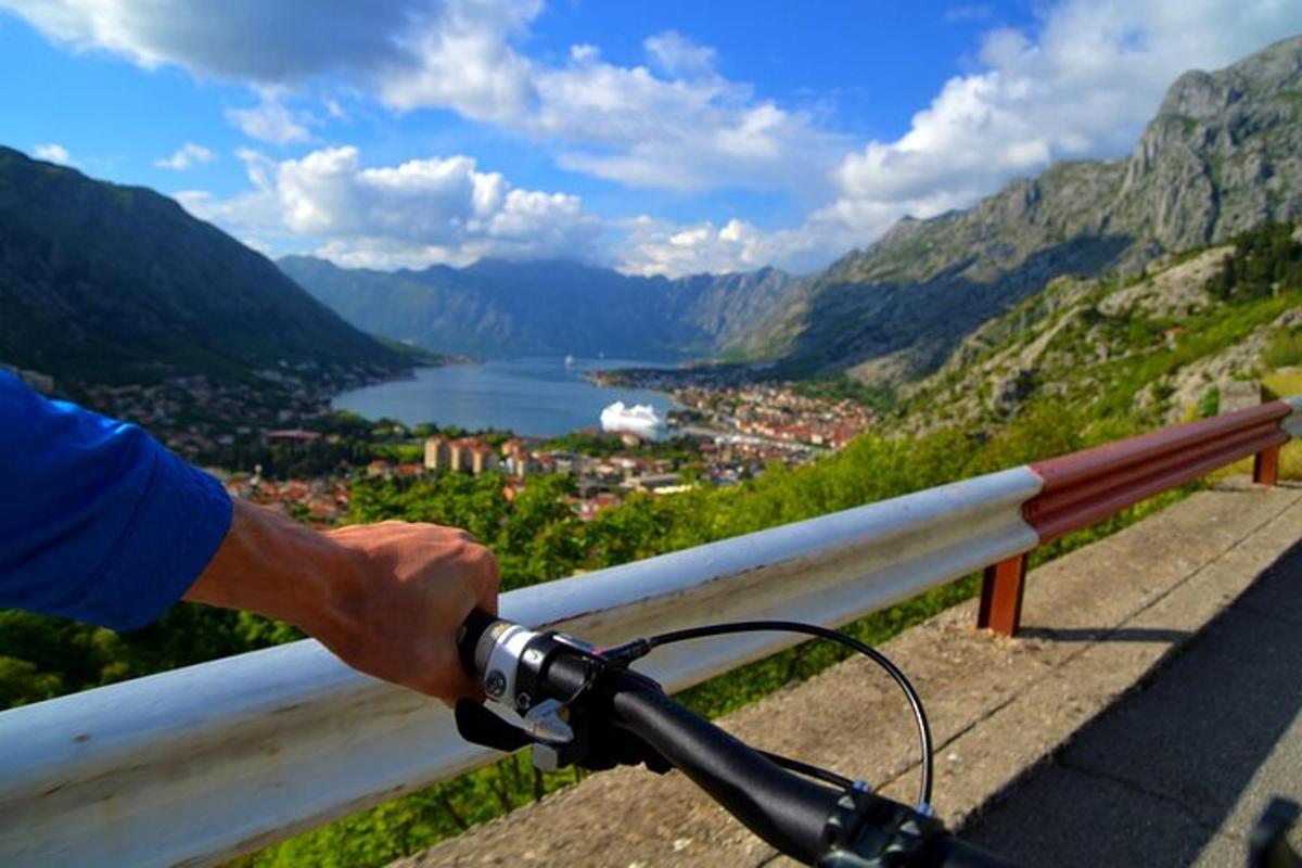 osoba jedoucí na kole přes zábradlí s výhledem na jezero