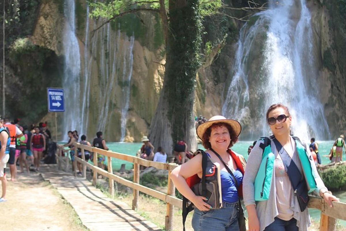 two women standing in front of a waterfall