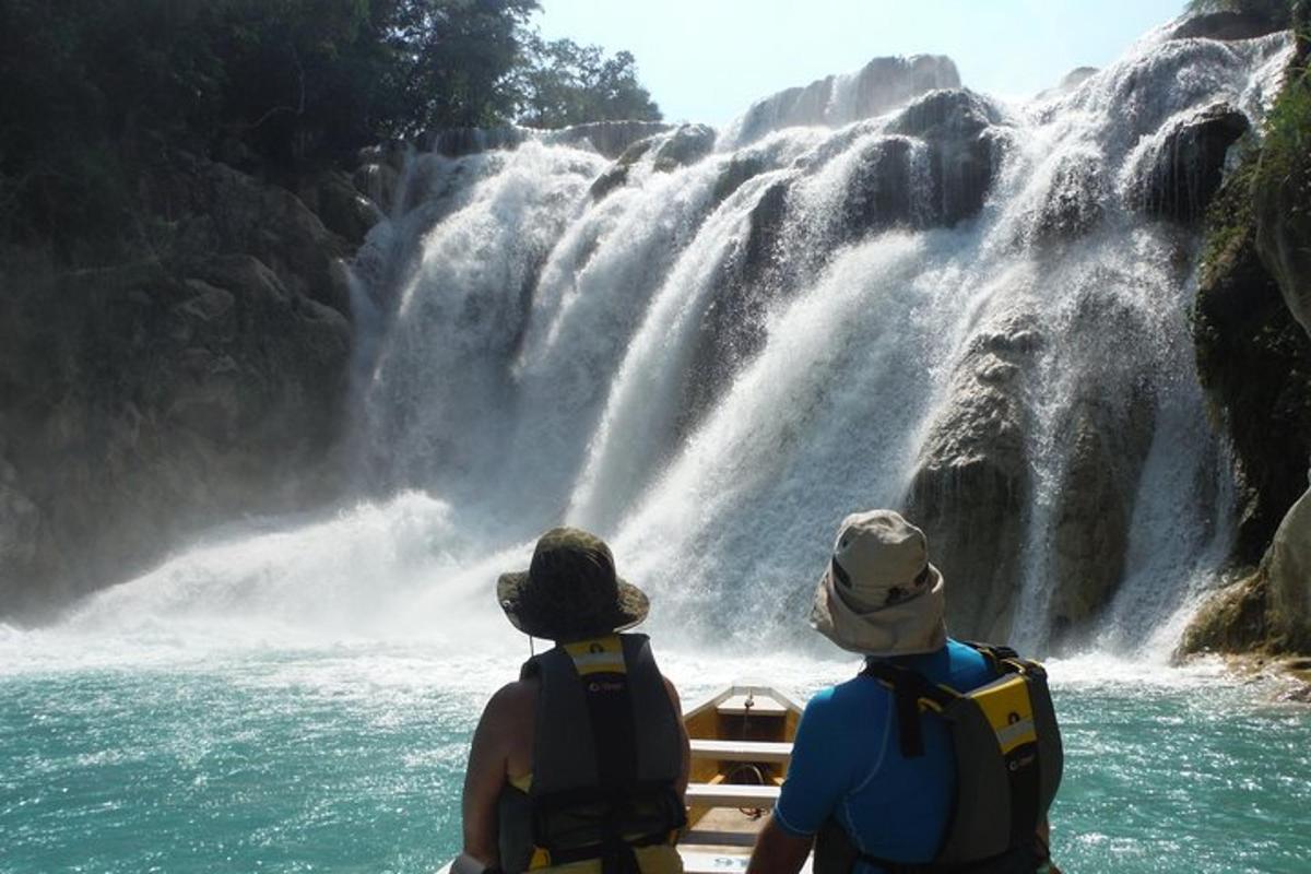 two people on a boat looking at a waterfall