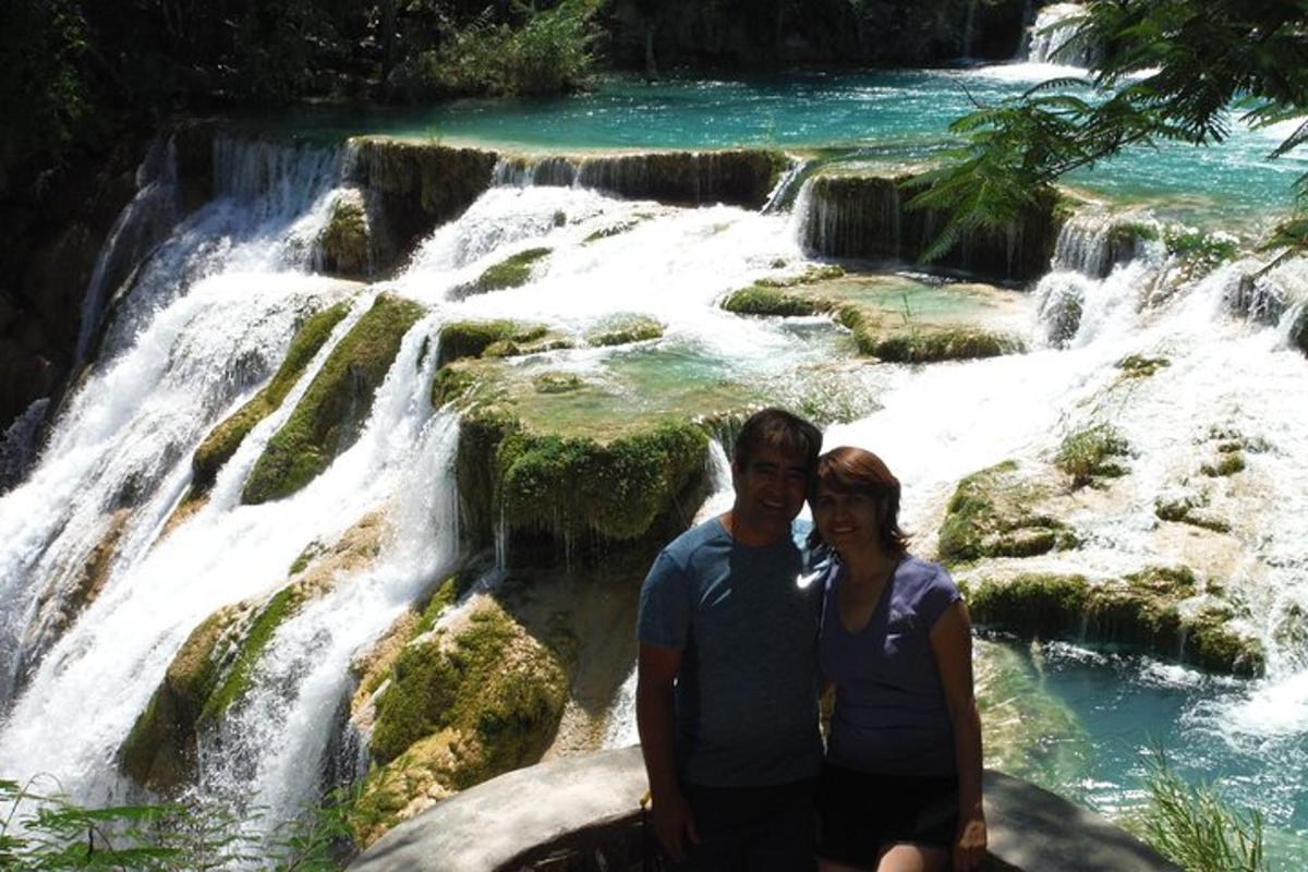 a man and woman standing in front of a waterfall