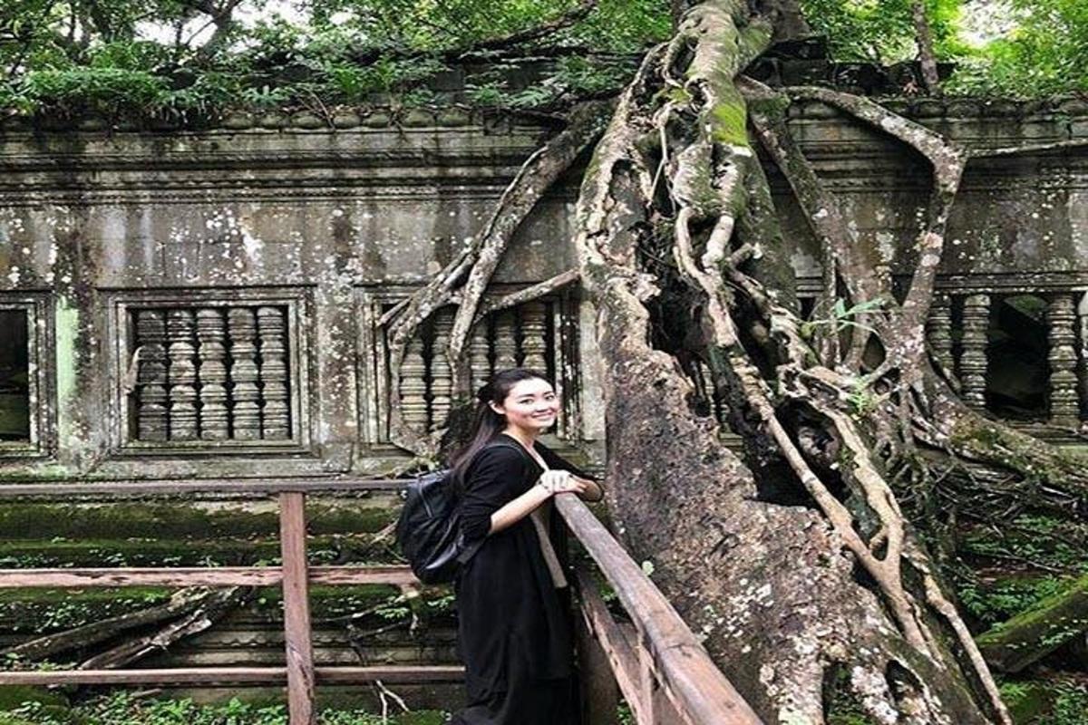 一位身穿黑色连衣裙的女子站在树旁