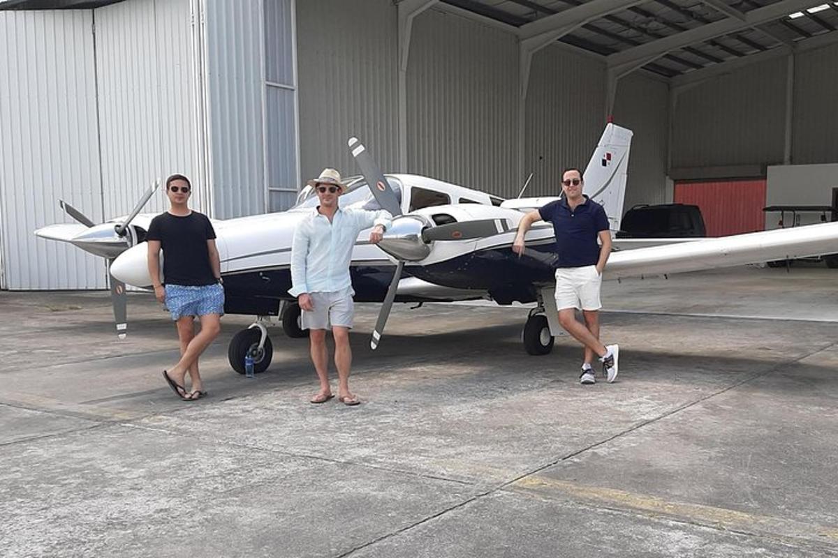 three men standing next to a small plane in a hangar