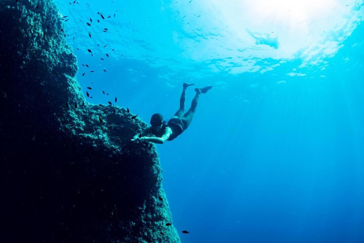 un uomo si tuffa in acqua da una scogliera