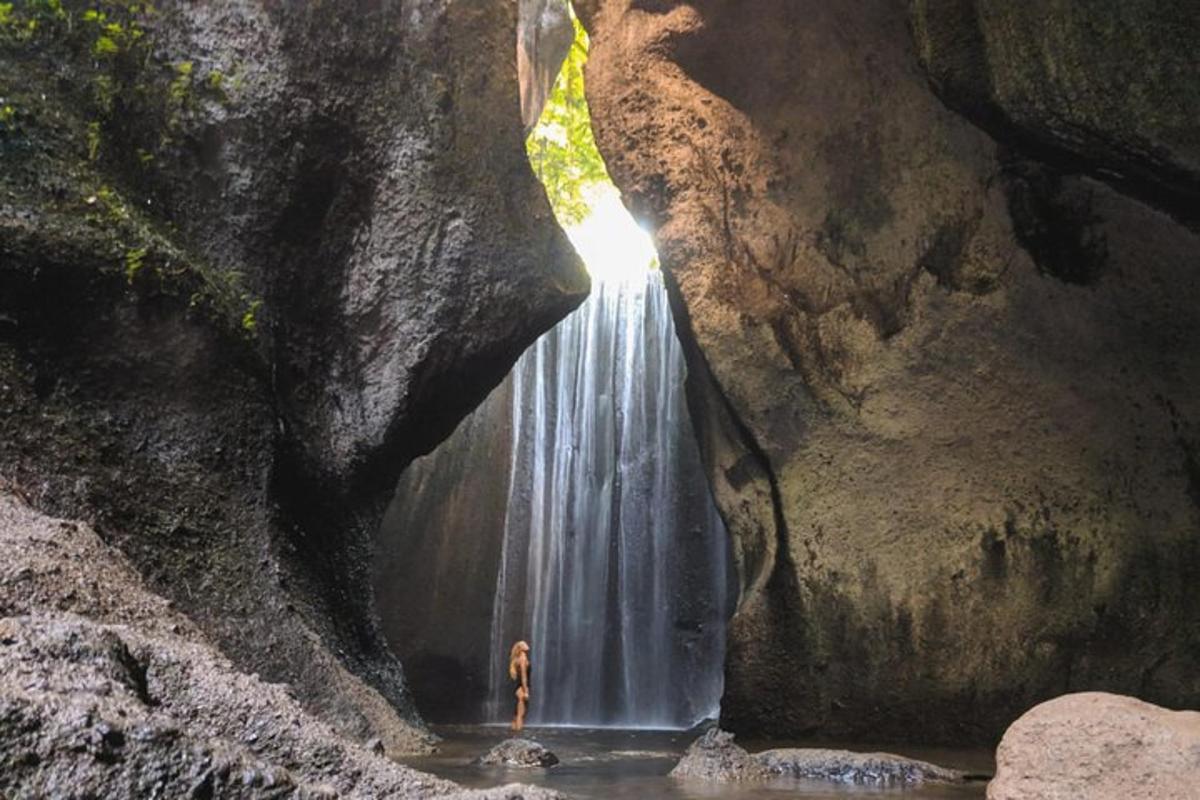 a person standing in front of a waterfall in a cave