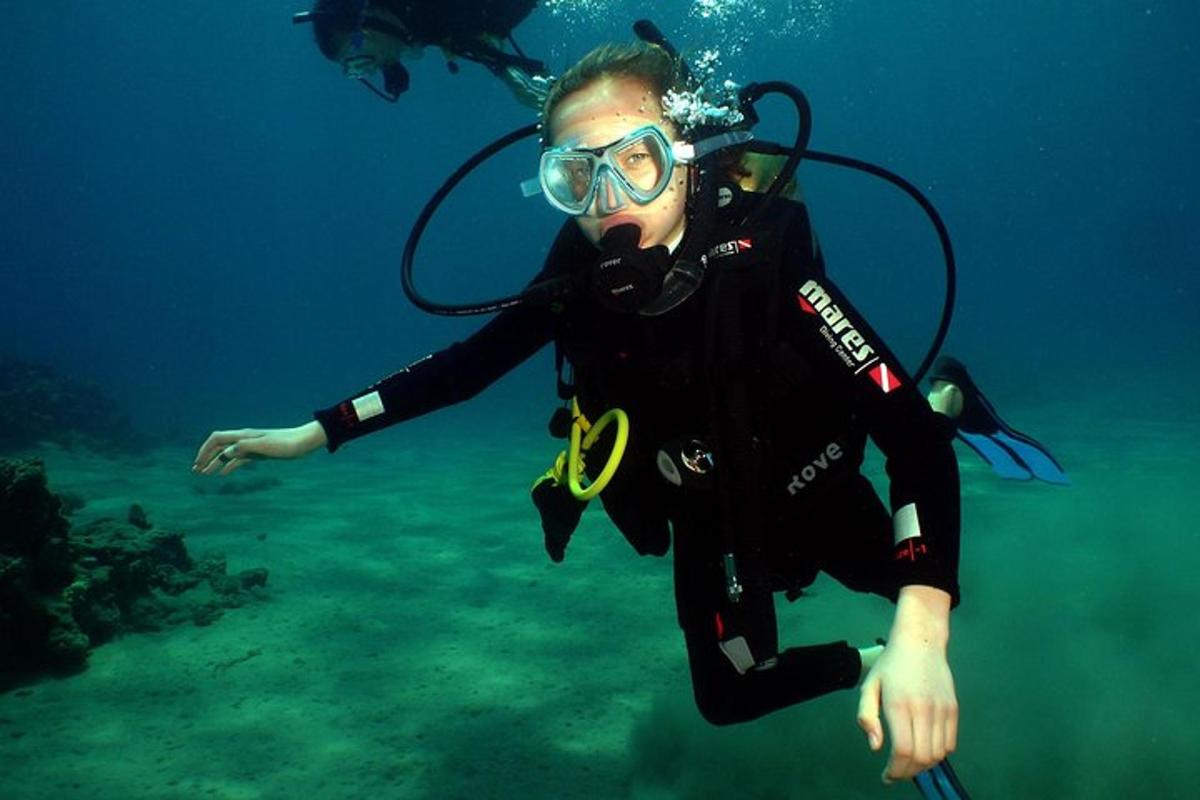 Žena v neoprenovém obleku a brýlích se potápí v oceánu