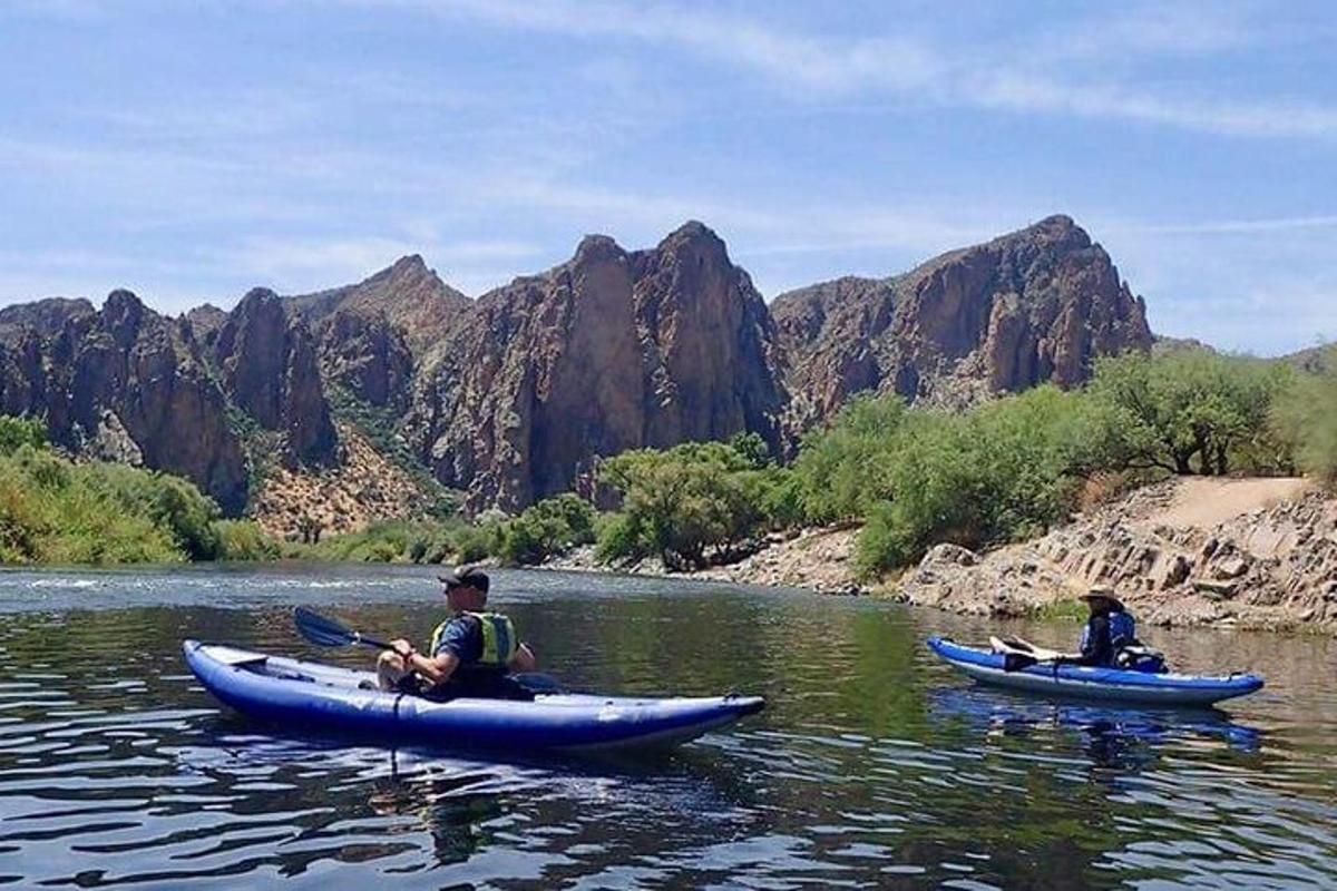 duas pessoas em caiaques em um rio com montanhas
